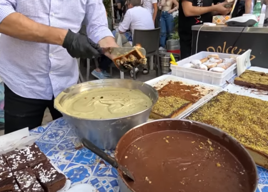 Sweets being prepared with creams and chopped nuts at a 2025 Ottobrata Zafferanese stall
